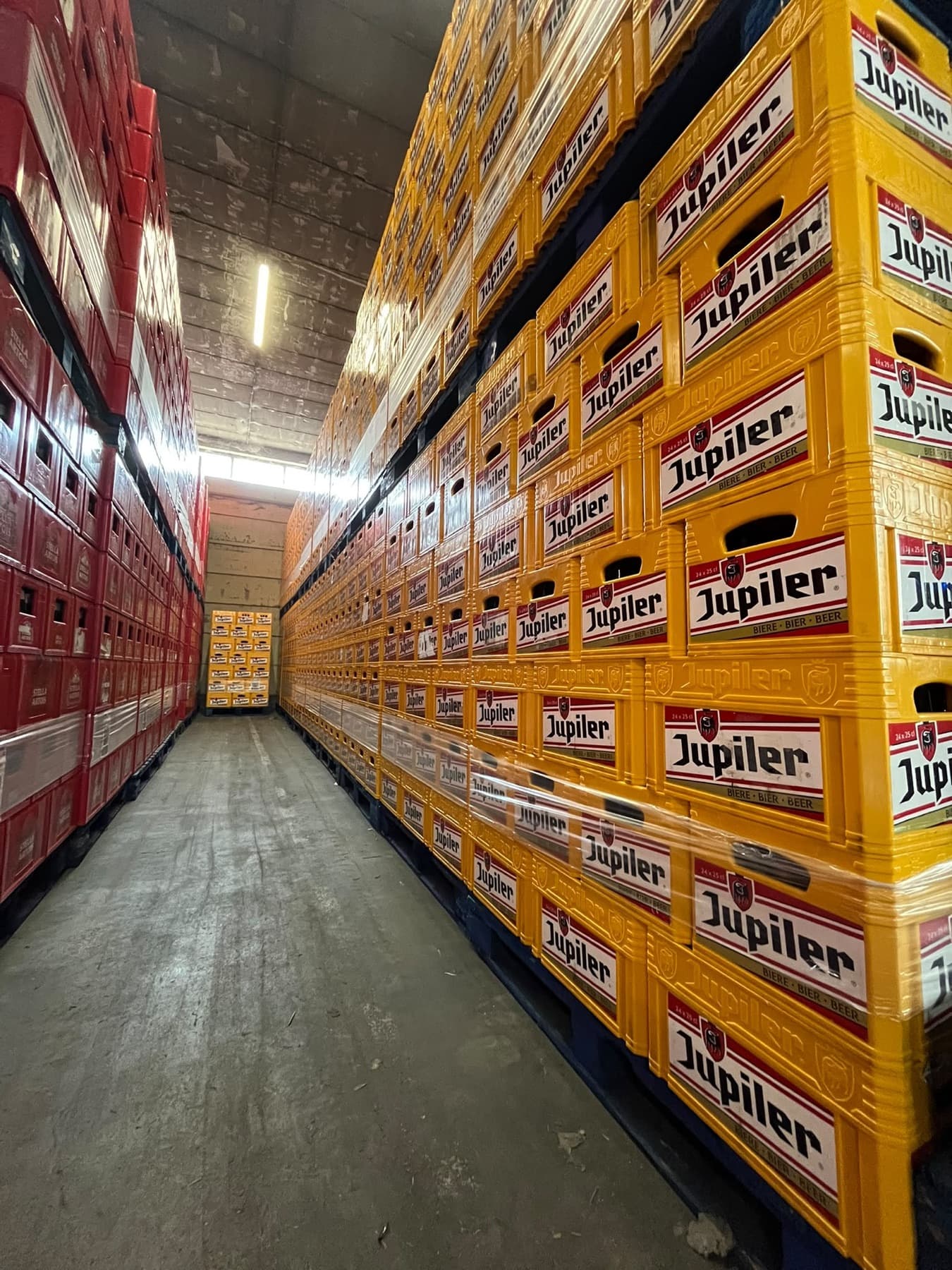 Gang in het magazijn met hoog opgestapelde bakken bier